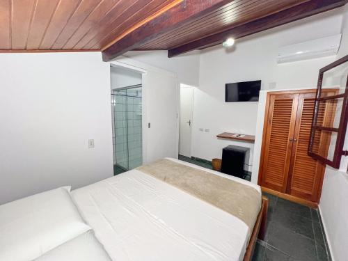 a bedroom with a white bed and a bathroom at Pousada Promessa Amanay antigamente Ubatuba Guest House in Ubatuba