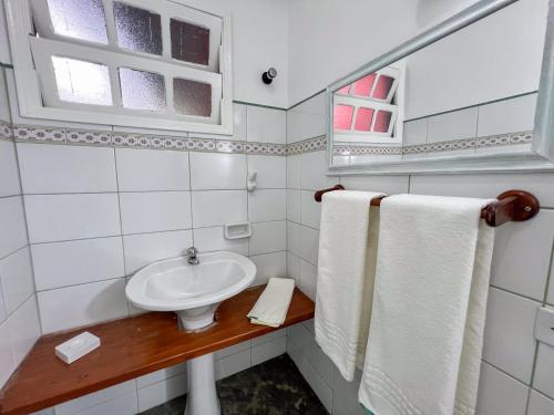 a bathroom with a sink and a window and towels at Pousada Promessa Amanay antigamente Ubatuba Guest House in Ubatuba