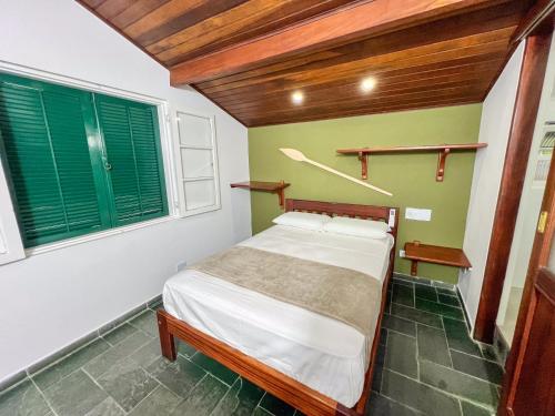 a small bedroom with a bed and green walls at Pousada Promessa Amanay antigamente Ubatuba Guest House in Ubatuba