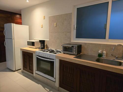 a kitchen with a stove and a sink and a refrigerator at " Los Mangos" 2 bedroom 2 Bathroom appartment at walking distance from the beach in Zihuatanejo
