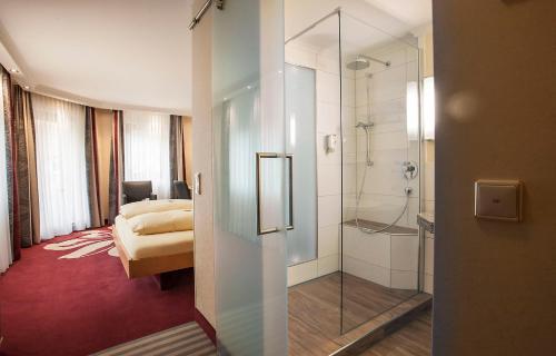 a hotel room with a shower and a bedroom at Forellenhof Rössle Hotel & Restaurant in Honau