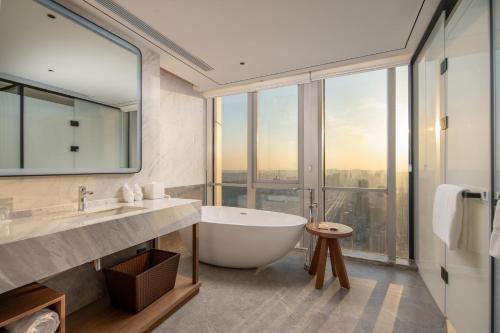 a bathroom with a tub and a large window at Hilton Garden Inn Hefei Feixi in Hefei