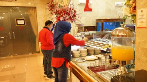 zwei Personen stehen in einer Küche und bereiten Essen zu in der Unterkunft Hotel Indah Palace Solo in Solo