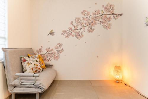 a room with a chair and flowers on the wall at Omotenashi HOTEL Asakusa in Tokyo