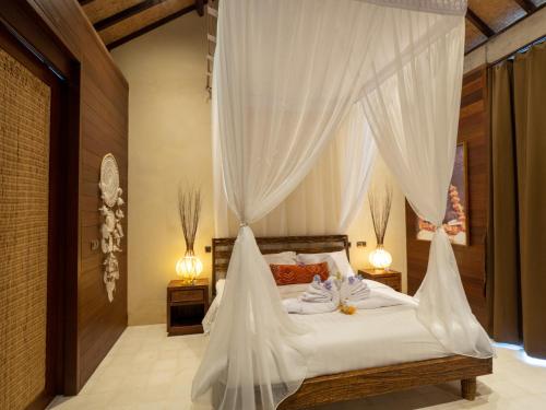 a bedroom with a canopy bed with white drapes at Ruby Romance Oceanside Villas in Tejakula