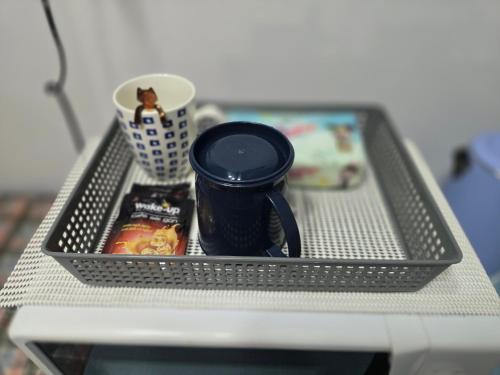 a tray with a coffee mug and a cup on a shelf at 104 Peaceful and Cosy apartment with cool fan near BTS with free WiFi in Bangkok