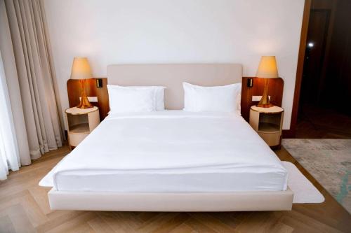 a bedroom with a large white bed with two lamps at Wyndham Residences Aqkol in Akkol'