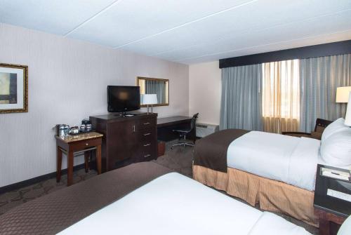 a hotel room with two beds and a desk at Wyndham Columbus in Worthington