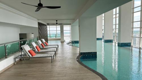 una piscina con una fila de sillas en un edificio en Tri Tower Residence 走路3分钟到新加坡马来西亚海关15分钟到新加坡 Walk 3 Minutes to CIQ, 15 Minutes to Singapore, en Johor Bahru