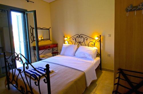 a bedroom with a bed with white sheets and a mirror at Akti Kamares in Kamáres