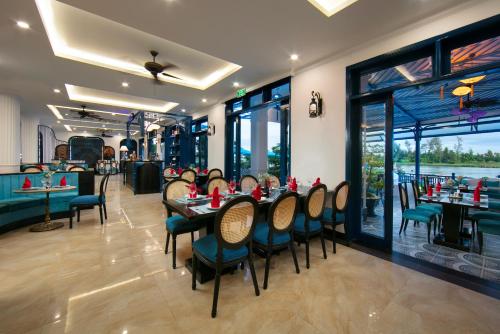 a dining room with tables and chairs and windows at Silk River Hoi An Hotel & Spa in Hoi An