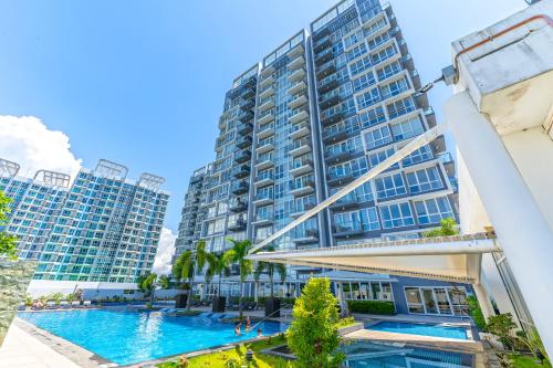 a large apartment building with a swimming pool and palm trees at Mactan Newtown - 1BR Stunning Ocean View and City View in Mactan