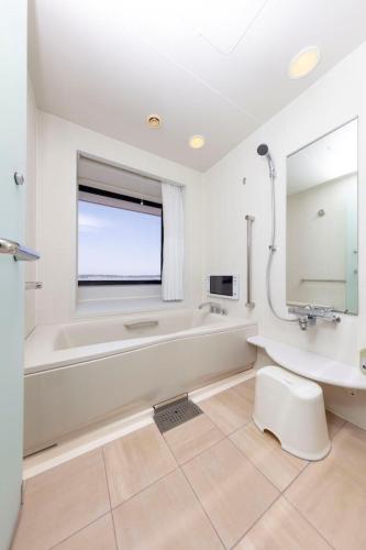 a white bathroom with a tub and a sink at Centrair Hotel in Tokoname