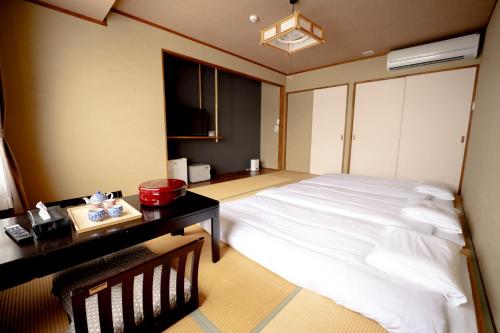 a bedroom with a large white bed and a desk at Hotel K Yuzawa 越後湯澤溫泉旅館 in Yuzawa