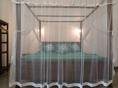 a bedroom with a canopy bed with white curtains at Plantation Surf Inn & Restaurant - Midigama in Midigama