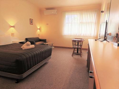 a bedroom with a bed and a couch and a table at St Georges Motor Inn in Melbourne