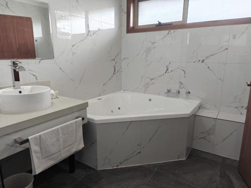 a white bathroom with a tub and a sink at St Georges Motor Inn in Melbourne