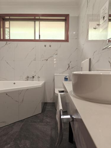 a white bathroom with a sink and a bath tub at St Georges Motor Inn in Melbourne