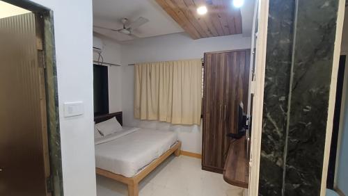 a small bedroom with a bed and a shower at Hotel Green Woods in Mahabaleshwar