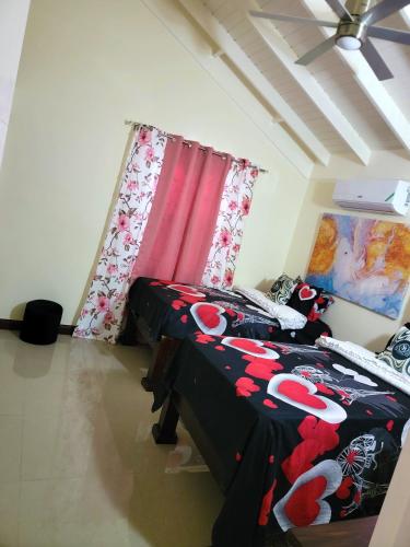 a bedroom with two beds and a red curtain at The Surada Bay 2 bedrooms in Old Harbour