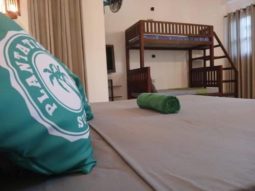 a bed with a green pillow on top of it at Plantation Surf Inn & Restaurant - Midigama in Midigama