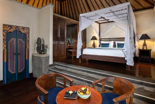 a bedroom with a bed and a table and chairs at Bidadari Private Villas & Retreat in Ubud