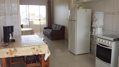a kitchen with a refrigerator and a table and a couch at Apartamentos Schmitt in Palhoça