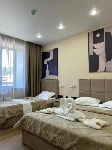 a hotel room with three beds with swans on them at Silkway Deluxe 1 in Semey