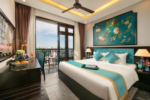 a bedroom with a large bed and a balcony at Silk River Hoi An Hotel & Spa in Hoi An