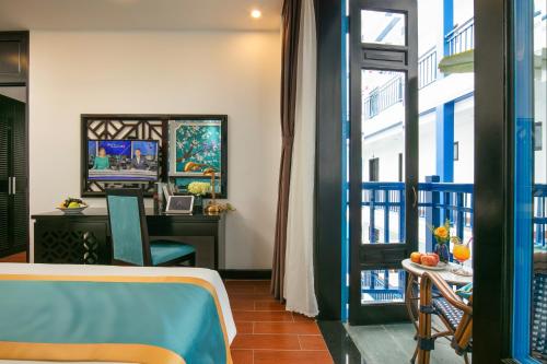 a room with a bed and a desk and a window at Silk River Hoi An Hotel & Spa in Hoi An