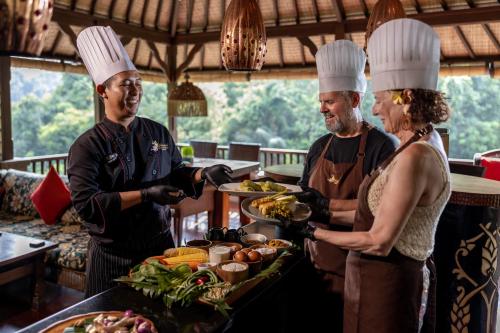 a man and woman in chefs hats preparing food at Bidadari Private Villas & Retreat in Ubud