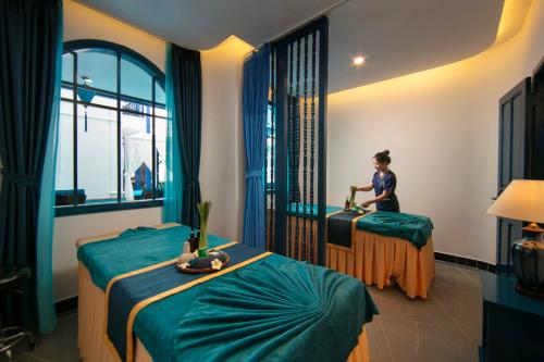 a woman standing in a room with two beds at Silk River Hoi An Hotel & Spa in Hoi An