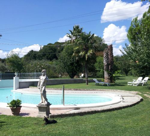 a statue and a cat sitting in the grass next to a pool at Luconi Affittacamere in Iesi