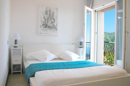 a white bedroom with a bed and a balcony at Affittacamere PZeta in Vernazza