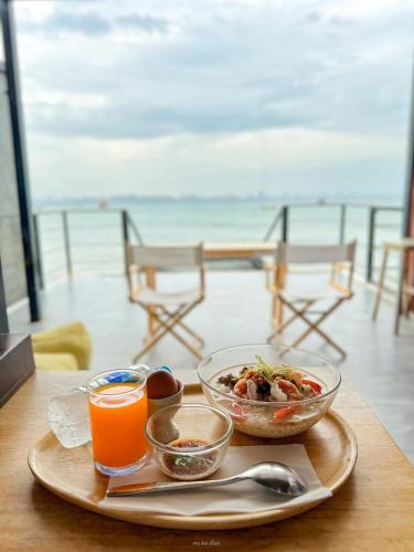 a table with a plate of food and orange juice at Baancoconutkohlarn in Ko Larn