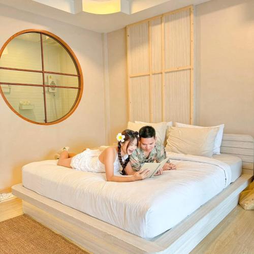 a bride and groom laying on a bed reading a book at Baancoconutkohlarn in Ko Larn