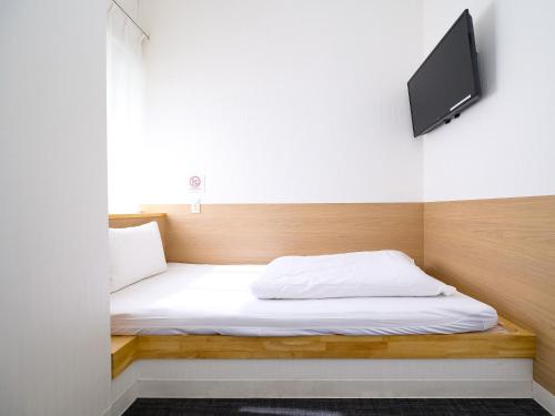 a bedroom with a bed with a tv on the wall at HOTEL THE CUBE Naha Kokusai Street in Naha