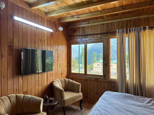 Luxury Timber Resorts and Hotels Cottages in Upper Neelum, Keran, AJK في Chak: غرفة نوم بسرير وتلفزيون وكرسي