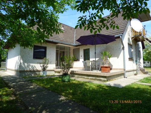 a house with an umbrella in the front yard at Fábián Apartman-ház in Szántód