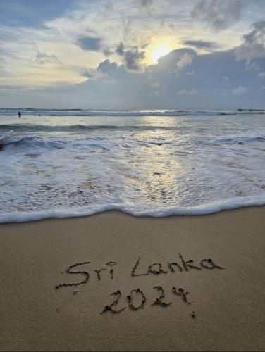 a sign written in the sand on the beach at Lucky Prince Villa in Aluthgama