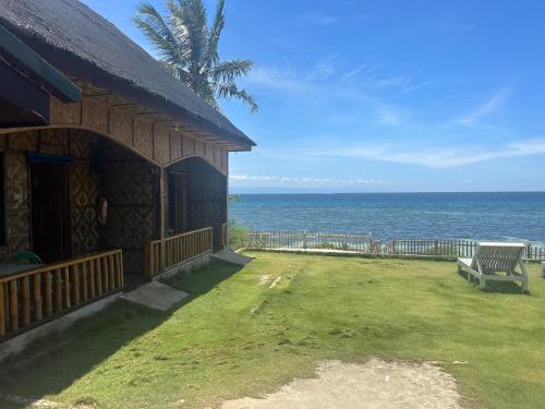 a house with a bench next to the ocean at Diamond De Siquijor Beach House in Siquijor