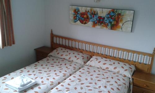 
a bed with two pillows and a painting on the wall at Hotel Rural Marcos in Rascafría
