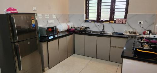 a kitchen with a black refrigerator and a sink at Nambiaparambil Arcade in Kakkayam