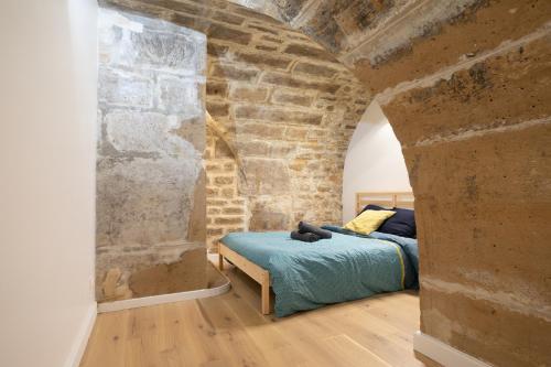 une chambre avec un lit dans un mur de briques dans l'établissement appartement Broca Mouffetard, à Paris