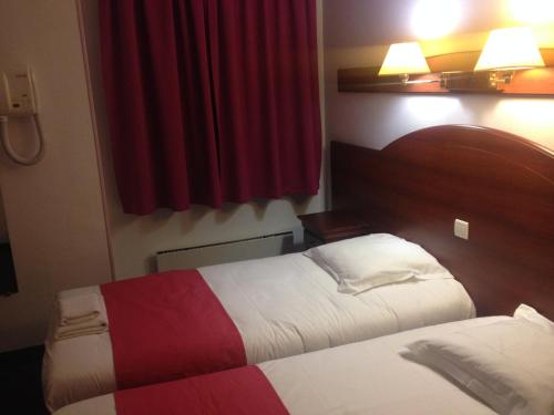 a hotel room with two beds and a red curtain at Hotel Couleurs Sud Centre-ville Gare Charleville-Mézières in Charleville-Mézières
