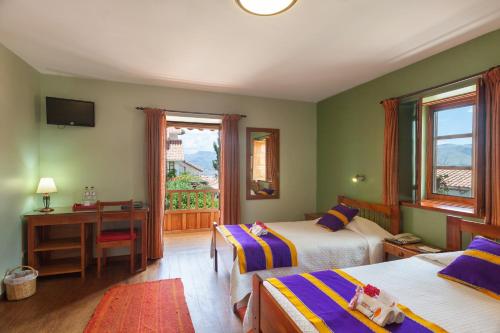 a bedroom with two beds and a desk and a window at Eco-Hotel Pension Alemana in Cusco