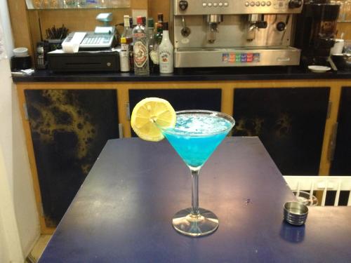 a blue drink in a martini glass on a table at Hotel Couleurs Sud Centre-ville Gare Charleville-Mézières in Charleville-Mézières