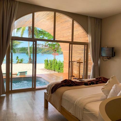 a bedroom with a large bed and a large window at Siam Beach Resort Koh Kood in Ko Kood