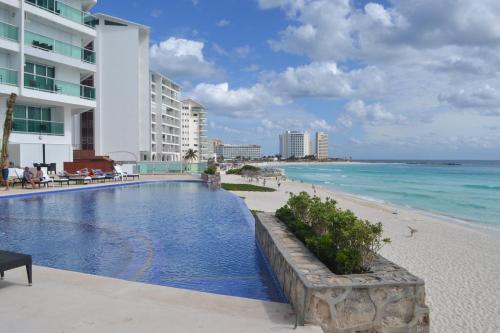 a swimming pool next to a beach next to a building at Ocean View Condo in Cancún