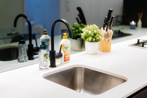 a kitchen sink with two faucets and bottles on it at Cozy Spacious Holiday 2B2B Melbourne CBD Apartment in Melbourne
